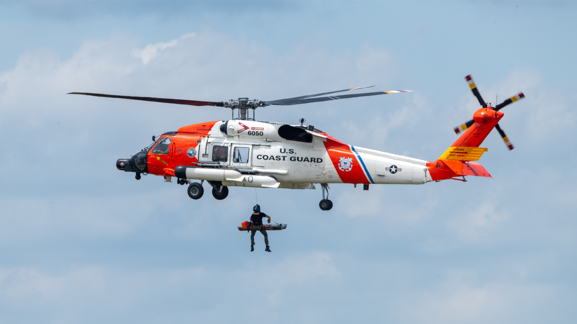 Image of a man being lowered out of a helicopter in the air